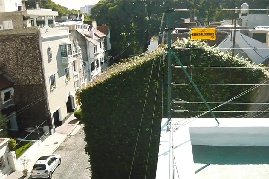 Cerco eléctrico sobre el cerco vivo de una casa