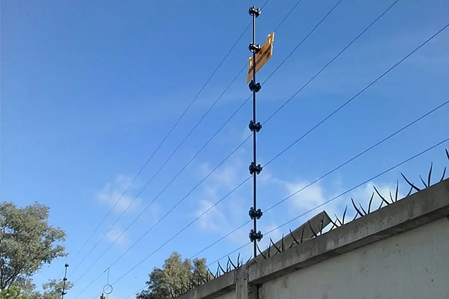 Cerco eléctrico sobre un muro blanco con cielo despejado