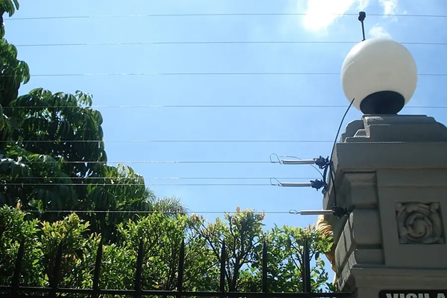 Cerco eléctrico sobre el pilar de entrada de una casa, junto a un farol
